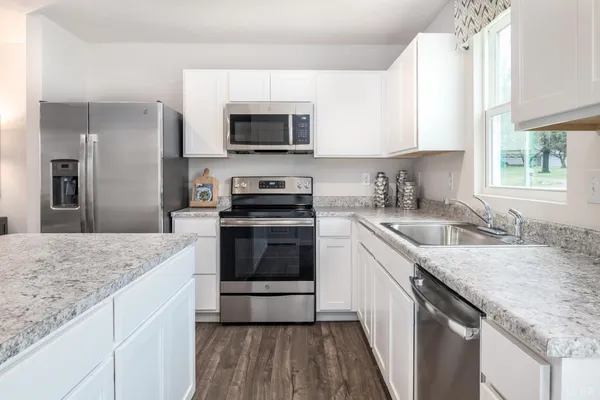 a kitchen with granite countertop a sink stove and microwave