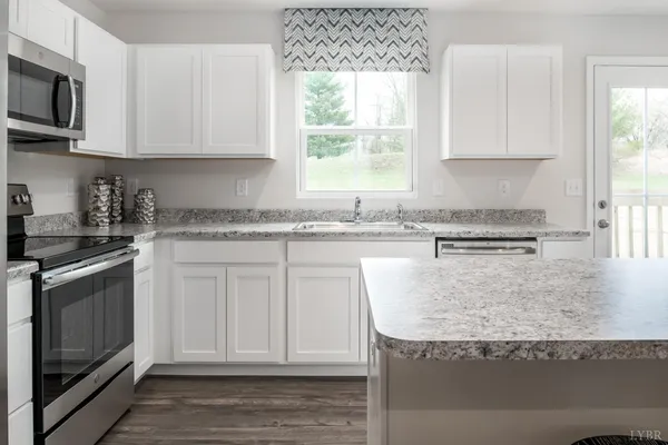 a kitchen with stainless steel appliances granite countertop a stove a sink and a microwave