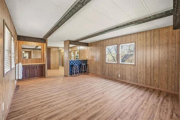 a view of an empty room with wooden floor and windows