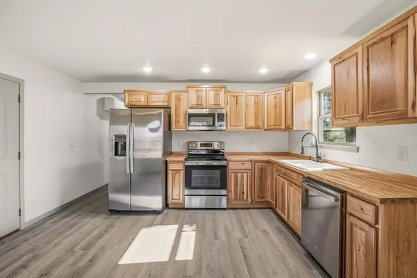 a kitchen with stainless steel appliances granite countertop a refrigerator a sink dishwasher a stove with wooden cabinets and floor