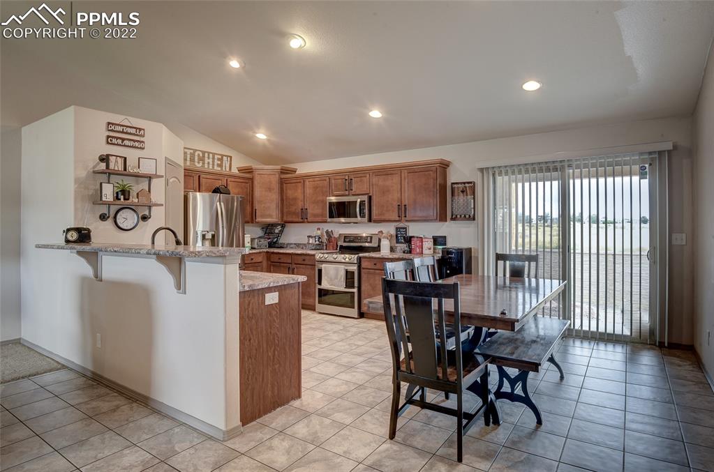5912 Polly Court Pueblo, CO 81008 - Photo 11 of 40 a kitchen with stainless steel appliances kitchen island granite countertop a table chairs and a refrigerator