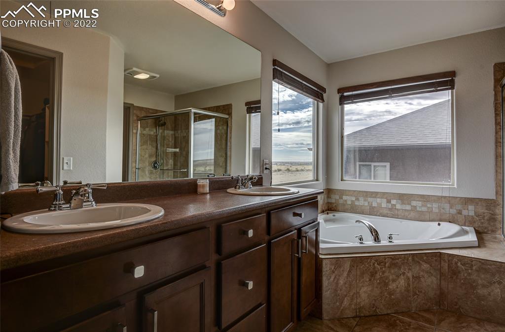 5912 Polly Court Pueblo, CO 81008 - Photo 25 of 40 a bathroom with a granite countertop sink and a bathtub next to a window