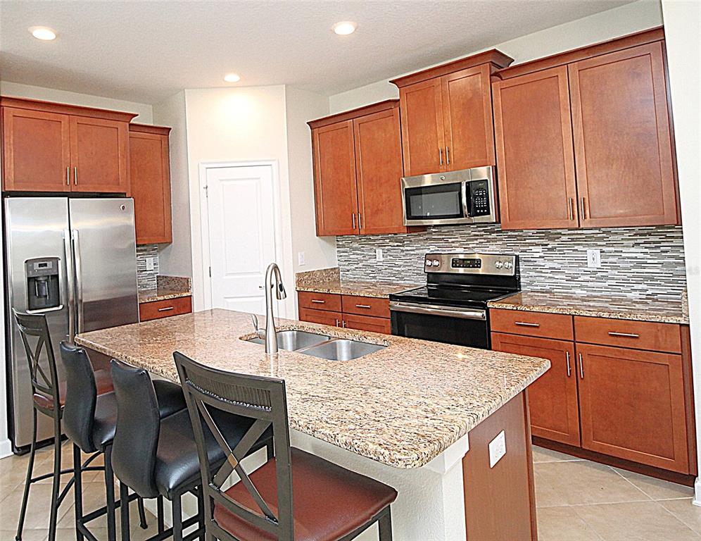 3752 Quaint Lane Clermont, FL 34711 - Photo 3 of 49 a kitchen with stainless steel appliances wooden cabinets a stove a sink and a microwave