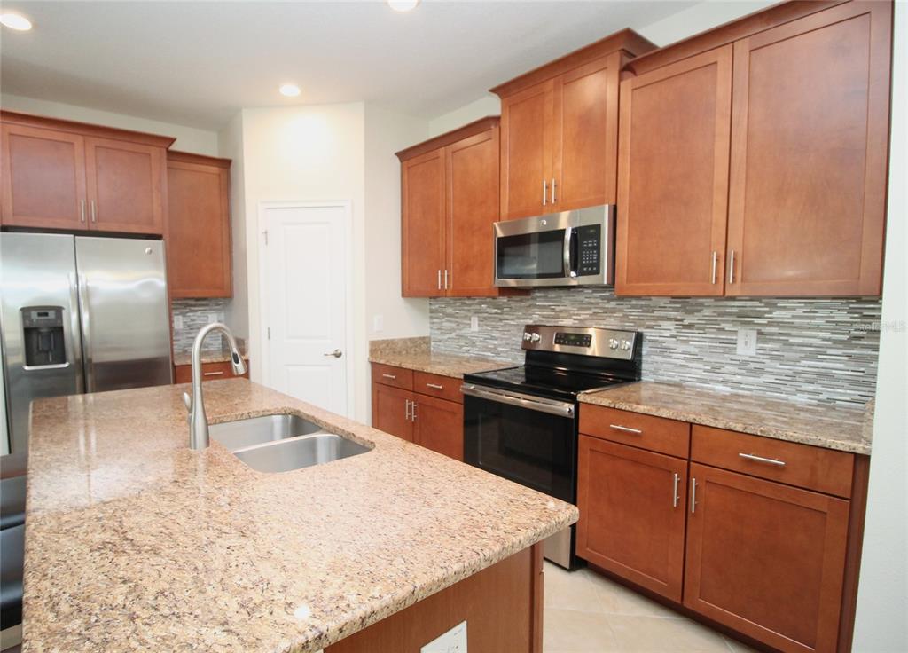 3752 Quaint Lane Clermont, FL 34711 - Photo 4 of 49 a kitchen with granite countertop a stove top oven microwave and refrigerator