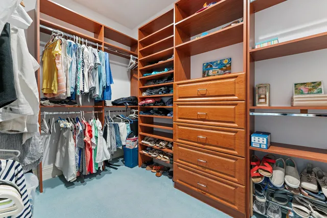 a view of walk in closet with clothes and shoes