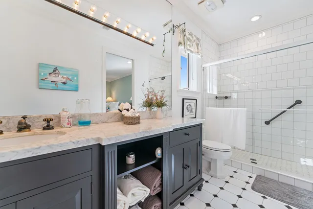 a bathroom with a sink a toilet a mirror and shower