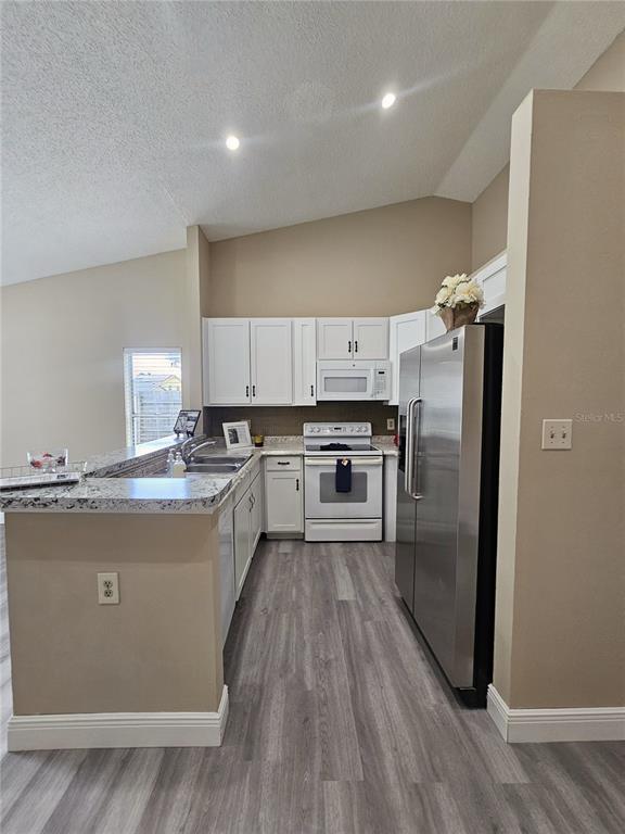 1025 Clovercrest Road Orlando, FL 32811 - Photo 7 of 27 a large kitchen with stainless steel appliances granite countertop a stove a sink dishwasher a refrigerator and white cabinets with wooden floor