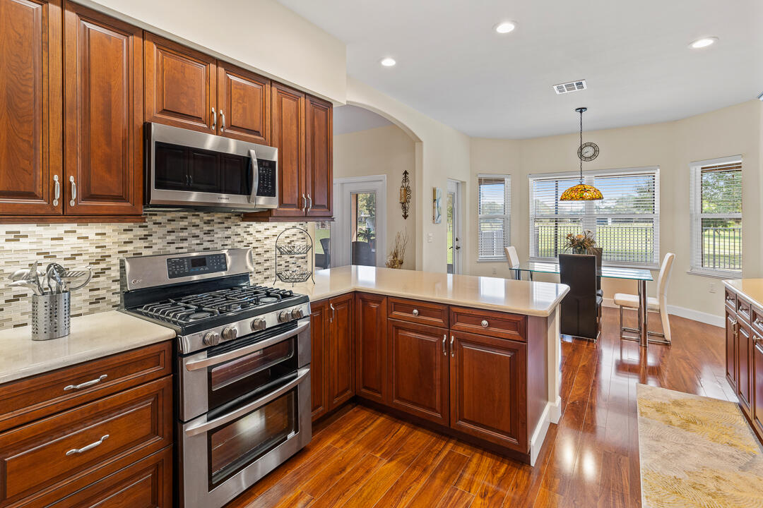 2774 Gentile Road Fort Pierce, FL 34945 - Photo 19 of 70 a kitchen with stainless steel appliances wooden cabinets and a stove top oven