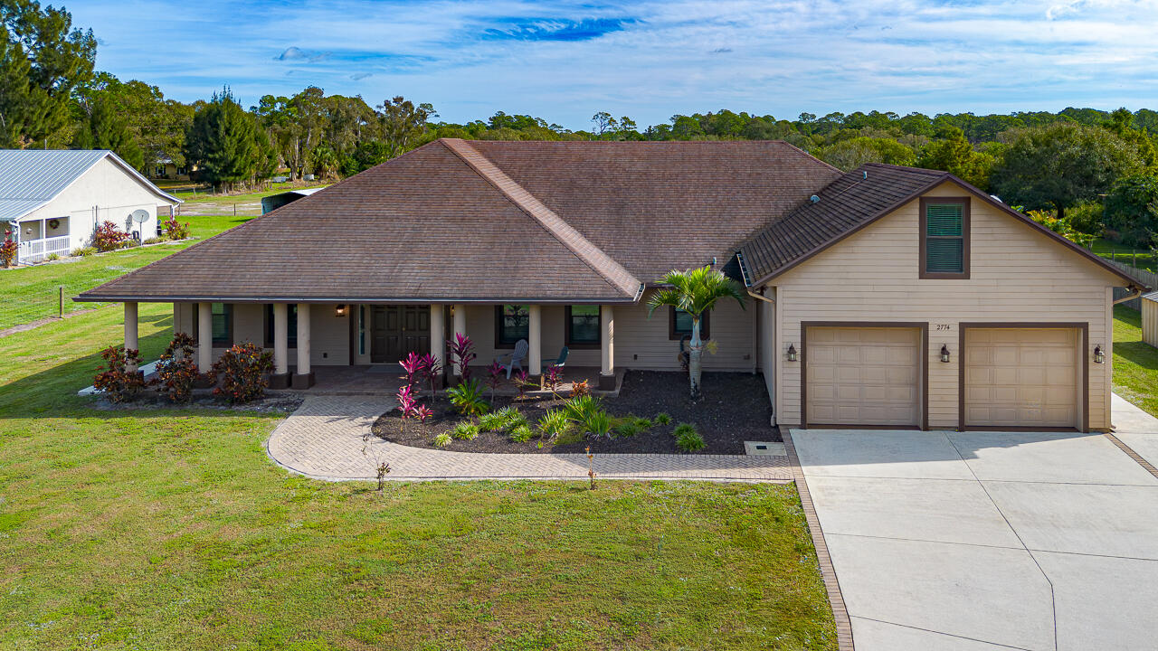 2774 Gentile Road Fort Pierce, FL 34945 - Photo 4 of 70 a front view of a house with a garden and yard