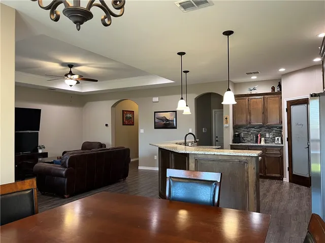a view of a kitchen with kitchen island stainless steel appliances a stove center island a dining table and chairs