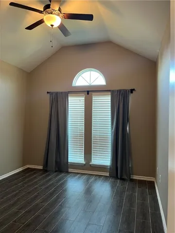 an empty room with wooden floor fan and window