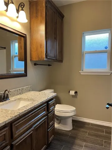 a bathroom with a granite countertop toilet sink and mirror
