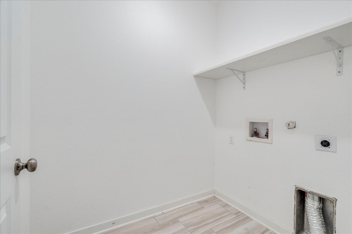 8008 Prairie Rye Drive Lago Vista, TX 78645 - Photo 28 of 40 Utility area featuring a white wall shelf, wood-finish flooring, and a brushed nickel door knob