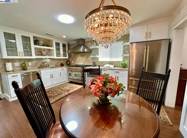 a kitchen with granite countertop a stove a sink dishwasher a refrigerator and cabinets with wooden floor