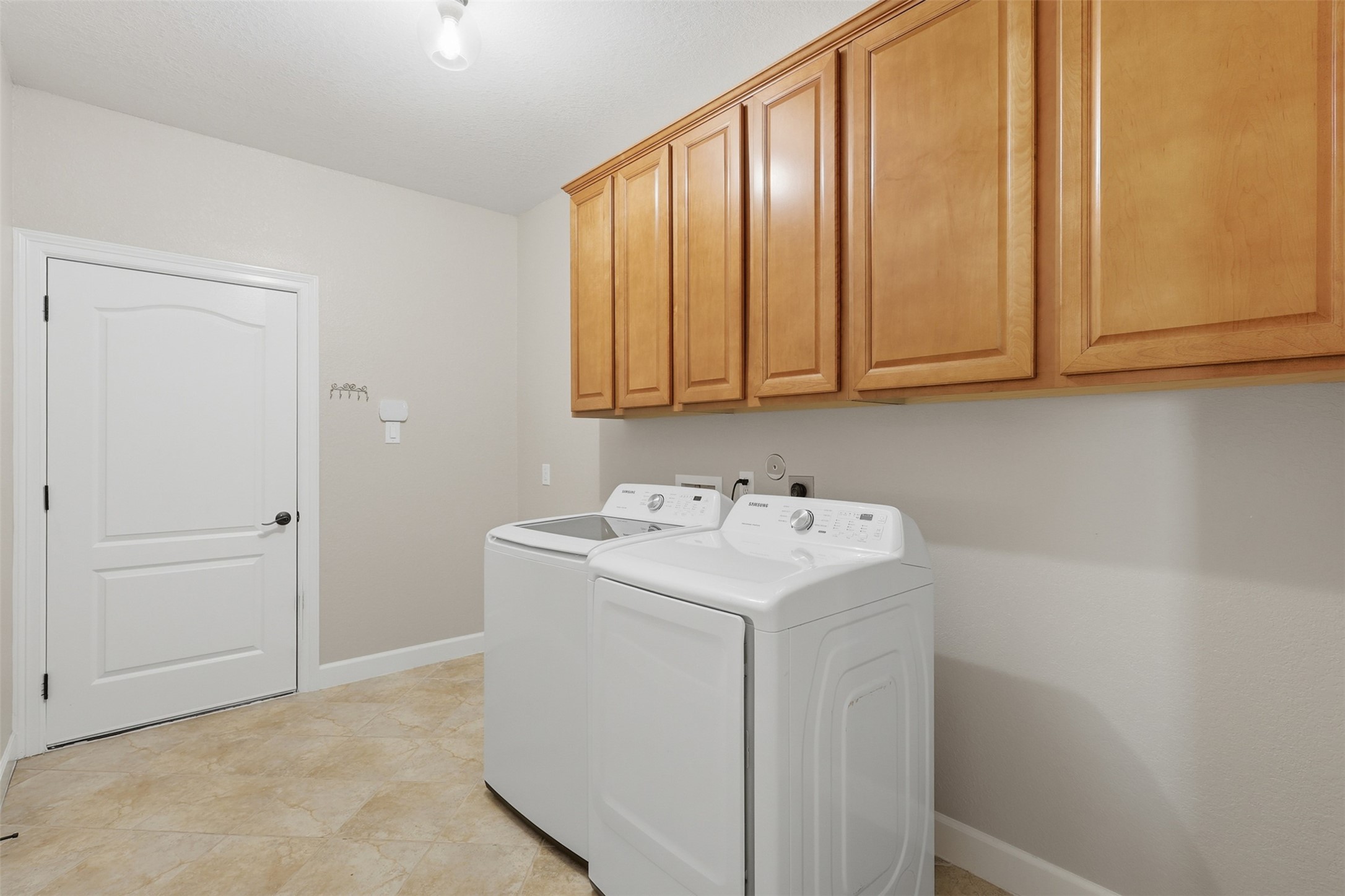 721 Rufina Street League City, TX 77573 - Photo 21 of 33 The spacious laundry room features abundant upper cabinetry for organized storage, durable tile flooring, and plenty of room for full-size appliances. Conveniently located, this well-appointed utility space keeps daily routines running smoothly.