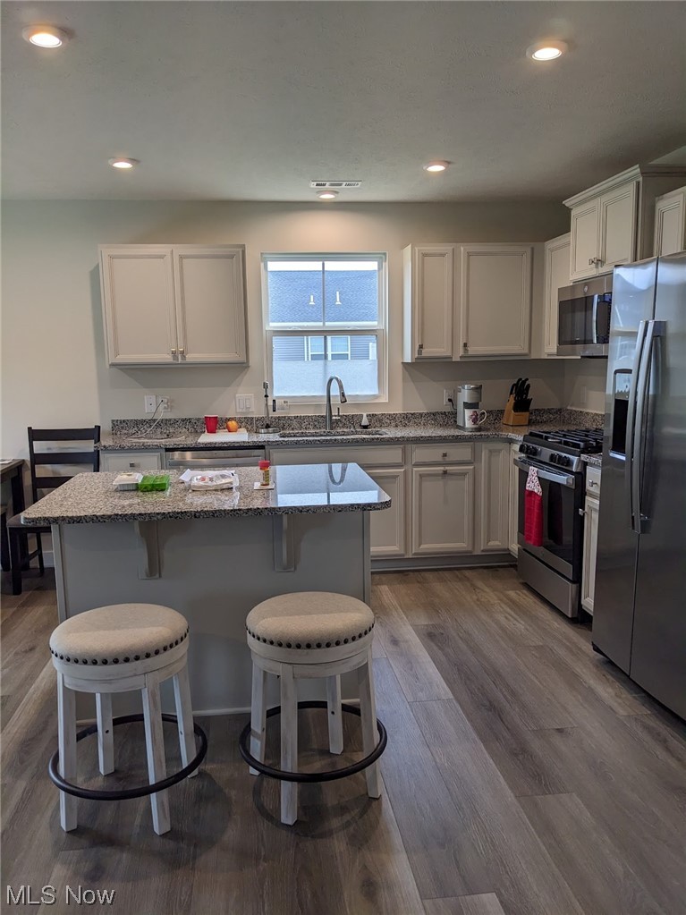 174 West Spring Drive Elyria, OH 44035 - Photo 7 of 19 Kitchen featuring sink, a breakfast bar, appliances with stainless steel finishes, dark hardwood / wood-style flooring, and white cabinetry