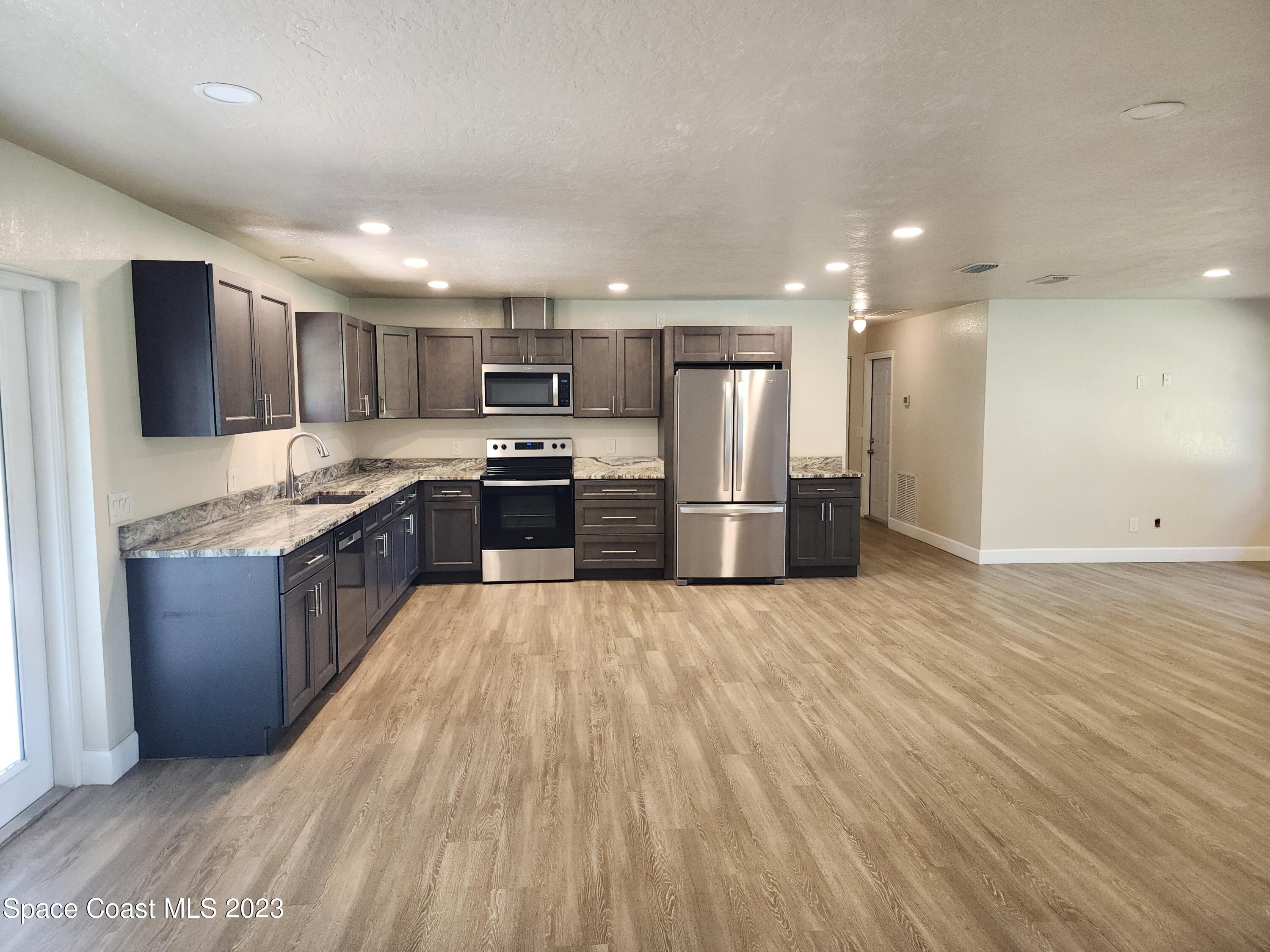 2745 Corey Road Malabar, FL 32950 - Photo 5 of 39 a large kitchen with stainless steel appliances granite countertop a large counter top and wooden floors