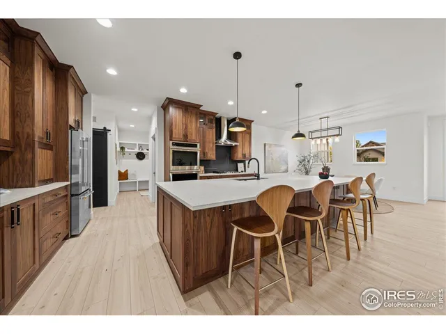 a open kitchen with stainless steel appliances kitchen island granite countertop a table chairs and a refrigerator