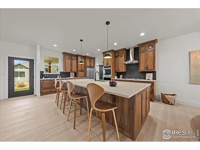a kitchen with stainless steel appliances granite countertop a table chairs and a refrigerator
