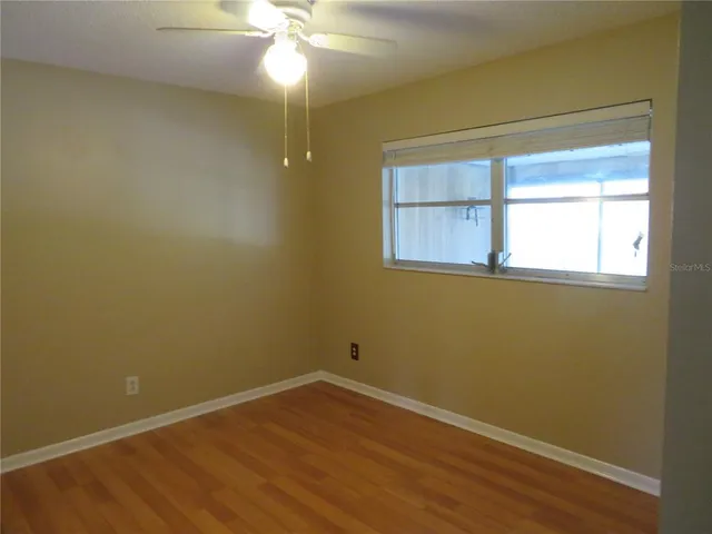 an empty room with a window and wooden floor
