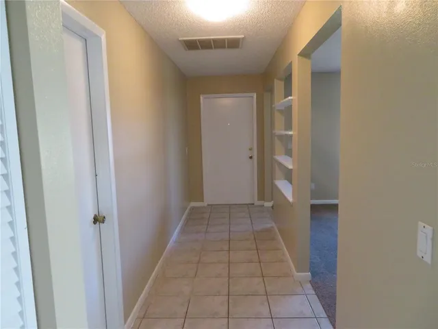 a view of a hallway with wooden floor and a bathroom