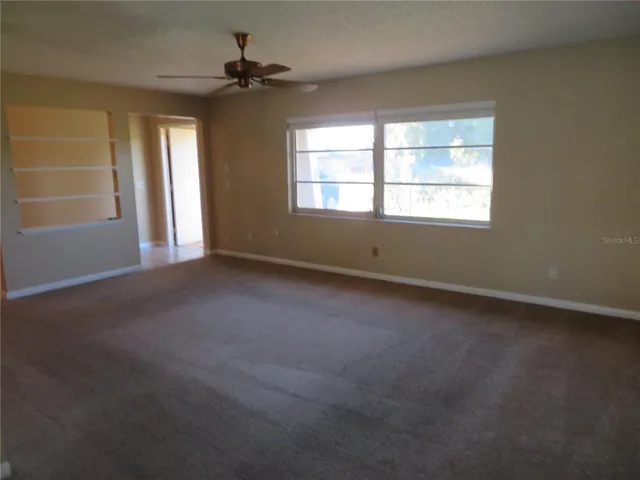 an empty room with windows and ceiling fan
