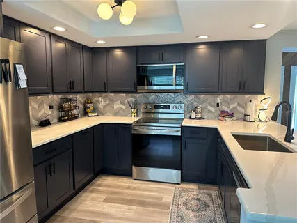 a room with stainless steel appliances kitchen island granite countertop a sink and cabinets