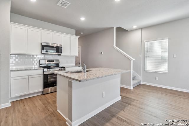 3921 Abbott Pass, Unit 102 St. Hedwig, TX 78152 - Photo 3 of 17 a kitchen with stainless steel appliances granite countertop a stove a sink and a refrigerator