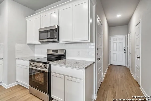 a kitchen with white cabinets and stainless steel appliances