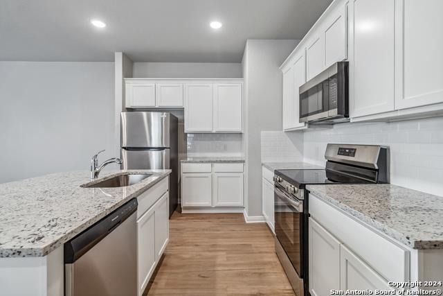 3921 Abbott Pass, Unit 102 St. Hedwig, TX 78152 - Photo 6 of 17 a kitchen with stainless steel appliances granite countertop a sink stove microwave and refrigerator