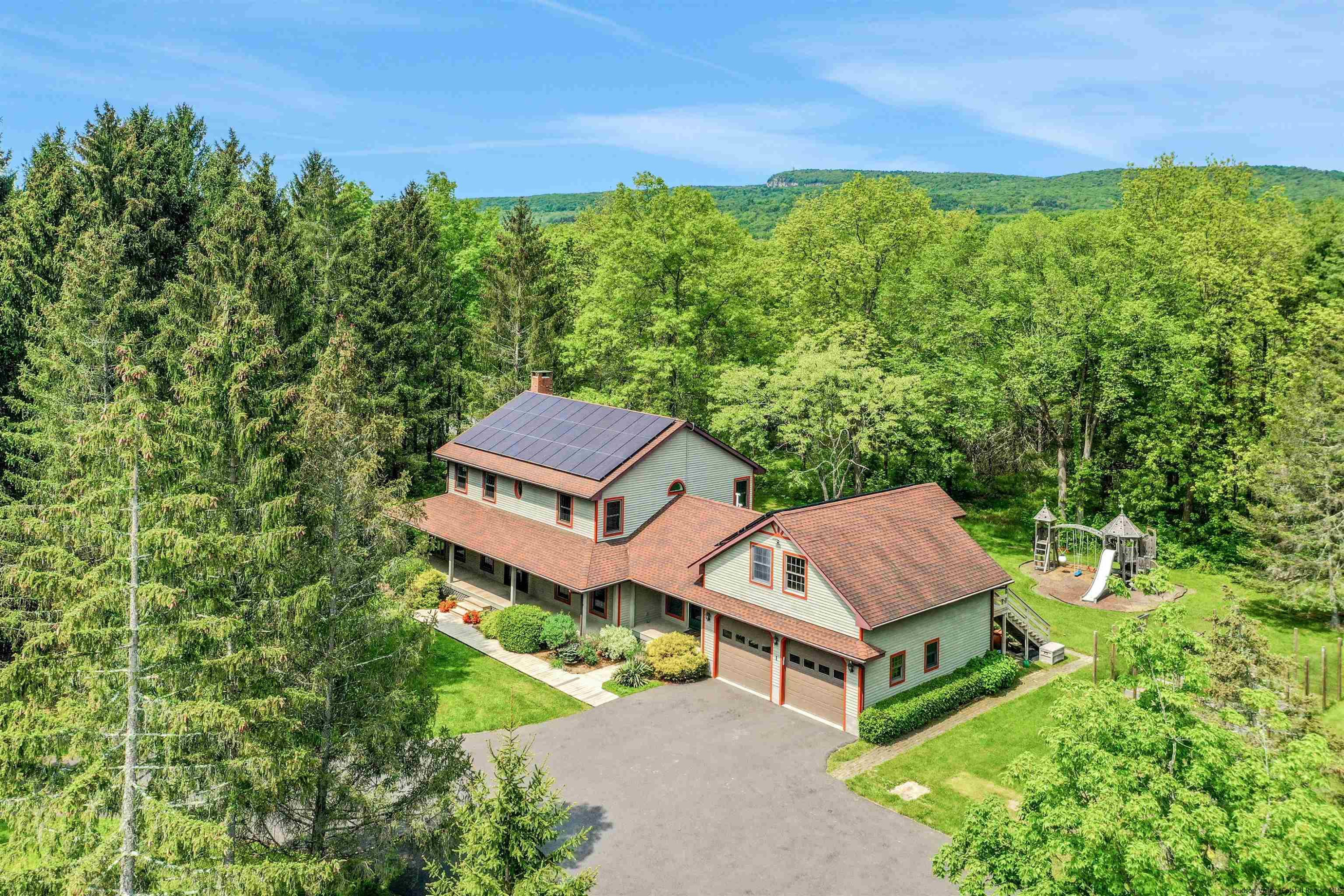 a view of a house with a big yard plants and large trees