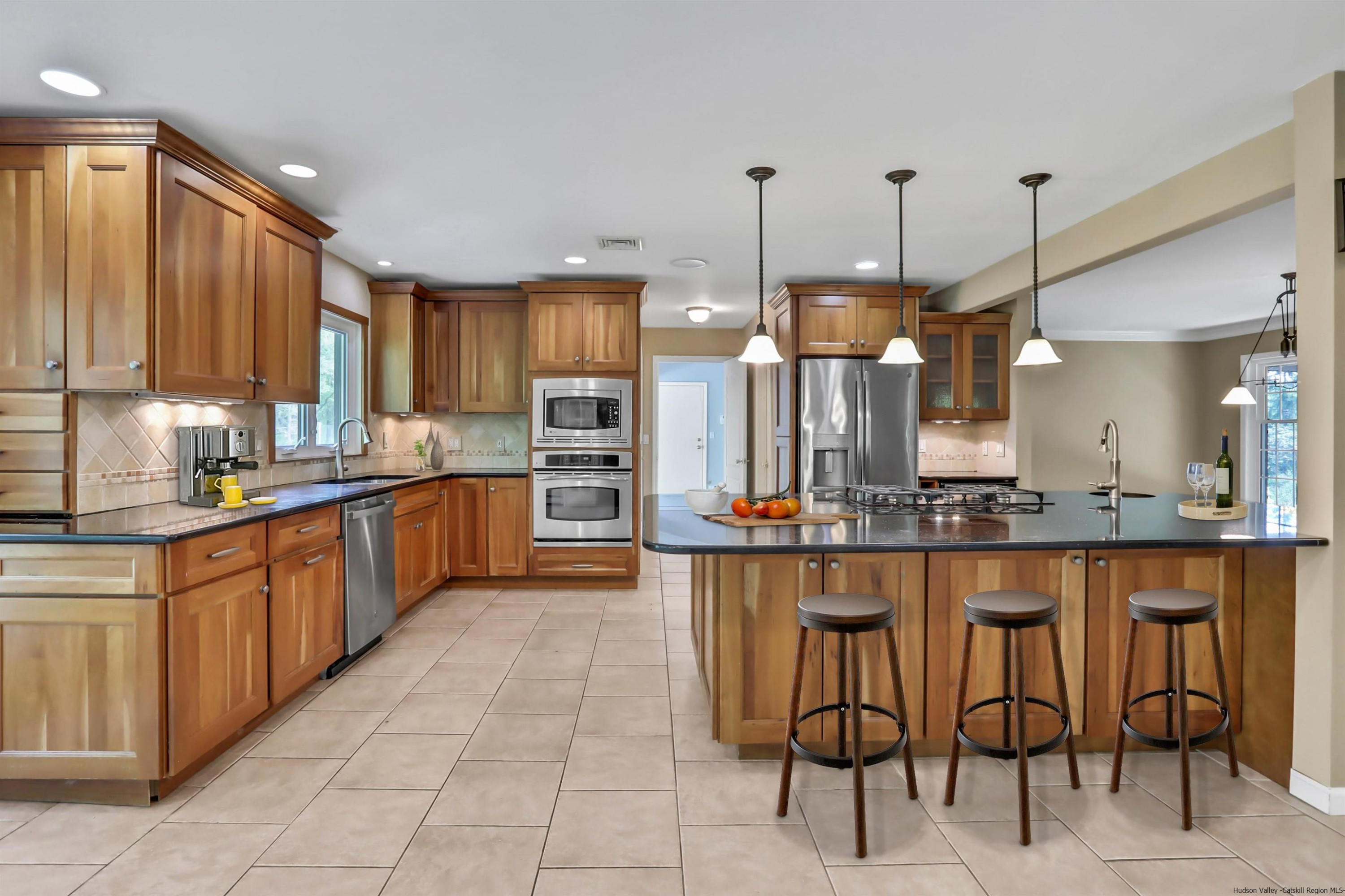 1 High Ridge Road, Unit KLEINKILL DR New Paltz, NY 12561 - Photo 15 of 30 a kitchen with stainless steel appliances kitchen island granite countertop a table chairs sink and cabinets