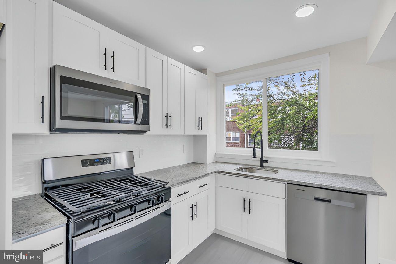 1300 East Sharpnack Street Philadelphia, PA 19150 - Photo 6 of 31 a kitchen with granite countertop a stove sink and microwave