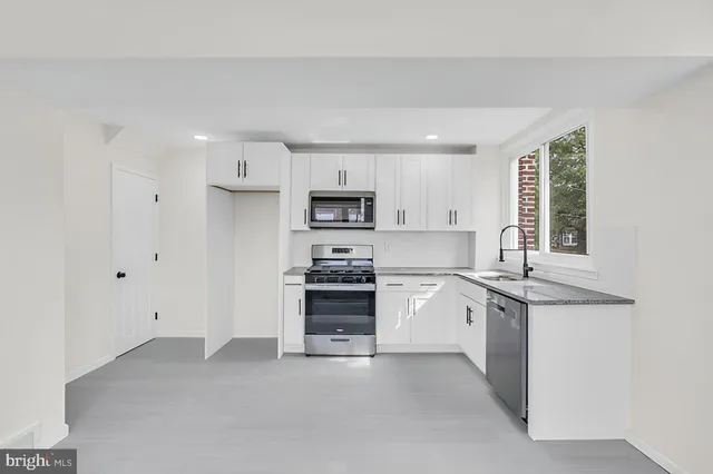 a kitchen with granite countertop white cabinets and stainless steel appliances