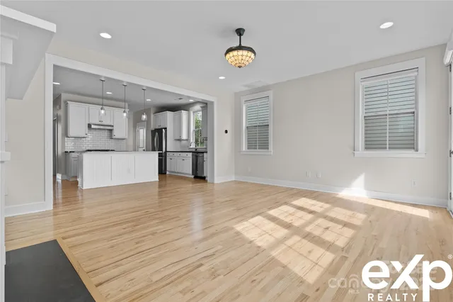 a view of empty room with wooden floor and kitchen view