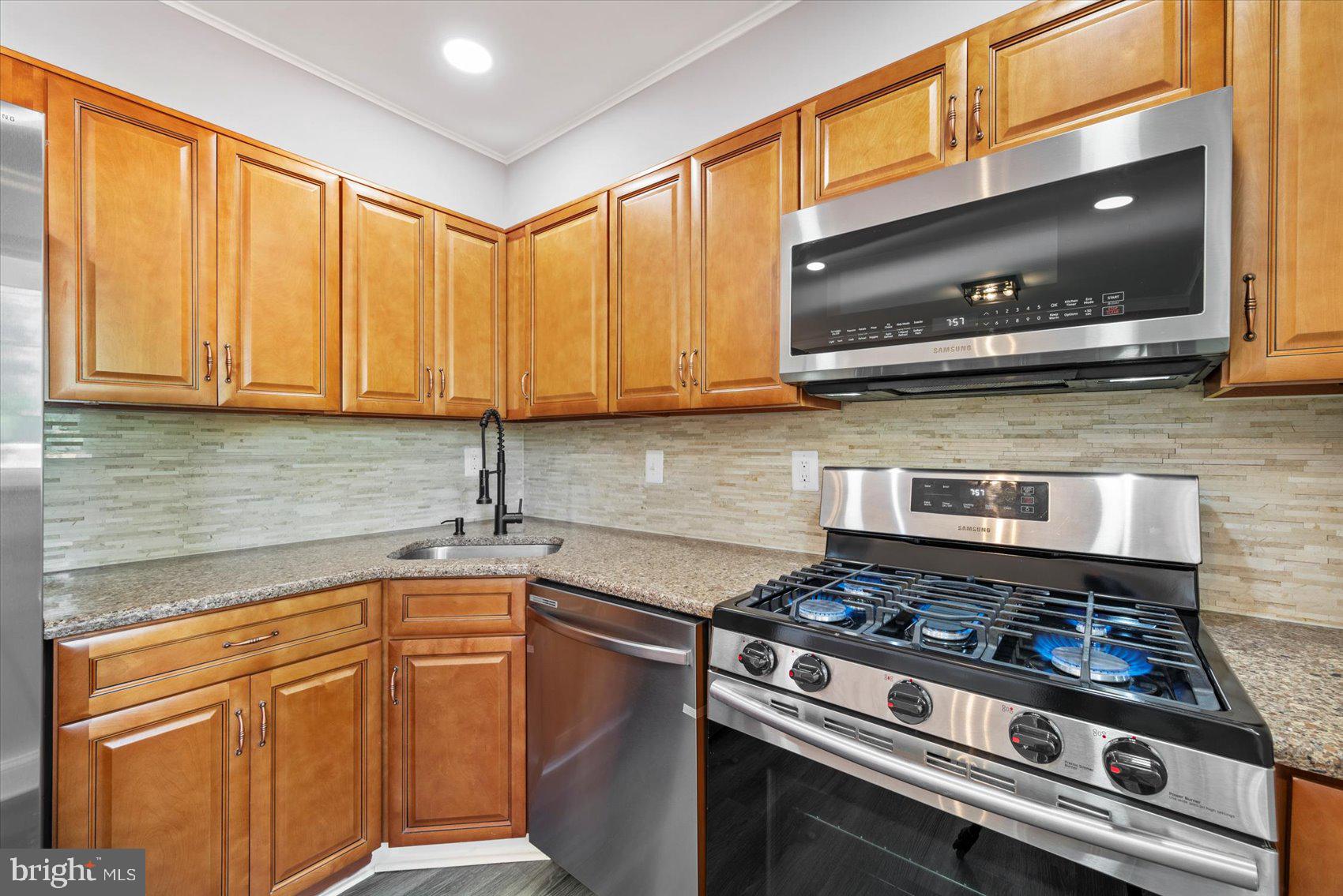 3107 Rheims Road Baltimore, MD 21244 - Photo 8 of 33 a kitchen with stainless steel appliances a stove a microwave and cabinets