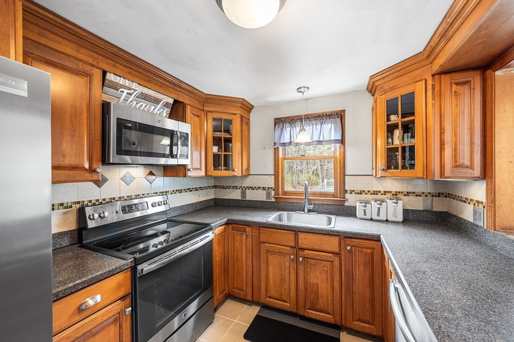 239 Upper County Road South Dennis, MA 02660 - Photo 8 of 38 a kitchen with stainless steel appliances granite countertop a sink a stove a microwave and wooden cabinets