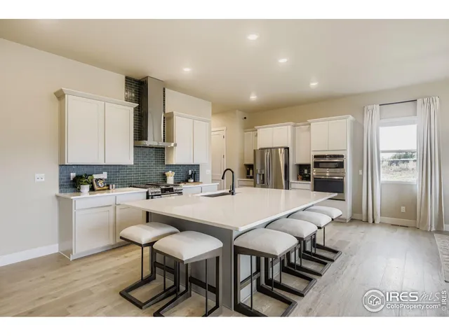 a kitchen with stainless steel appliances wooden floor and chairs