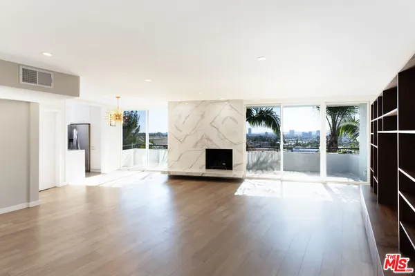 an empty room with wooden floor fireplace and windows