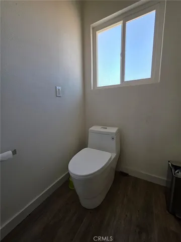 a white toilet sitting in a bathroom next to a window