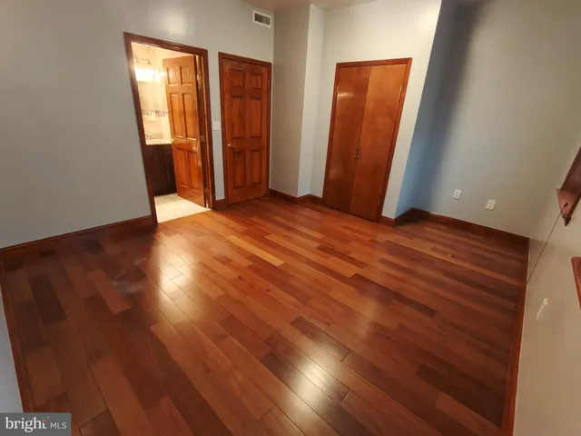 an empty room with wooden floor and closet