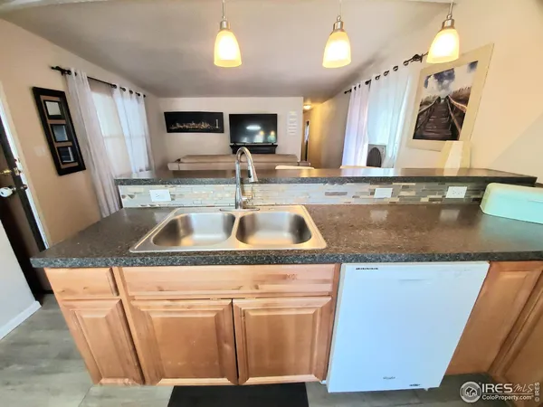 a view kitchen with granite countertop a sink and dishwasher with wooden cabinets