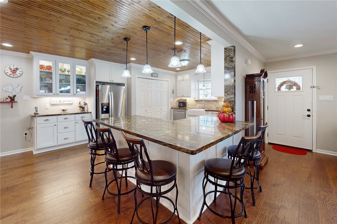 3710 Mancuso Road Bryan, TX 77808 - Photo 9 of 42 Kitchen with crown molding, glass insert cabinets, dark stone countertops, white cabinets, and hanging light fixtures
