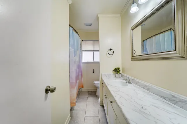 a bathroom with a granite countertop sink mirror and a toilet