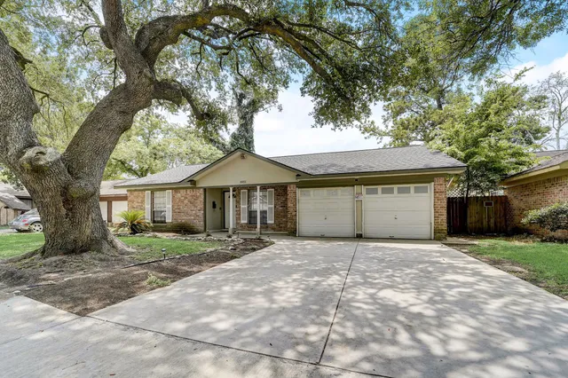 a front view of a house with a yard and large tree