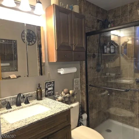 a bathroom with a granite countertop sink mirror vanity and toilet