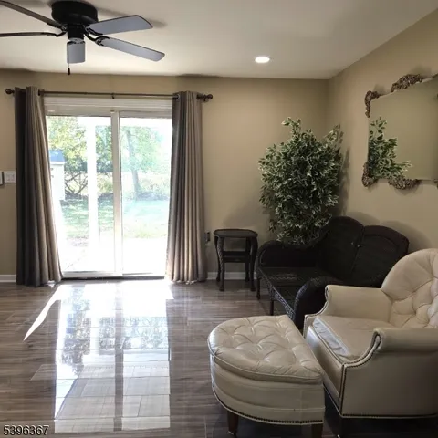 a view of a livingroom with wooden floor a flat screen tv and a window