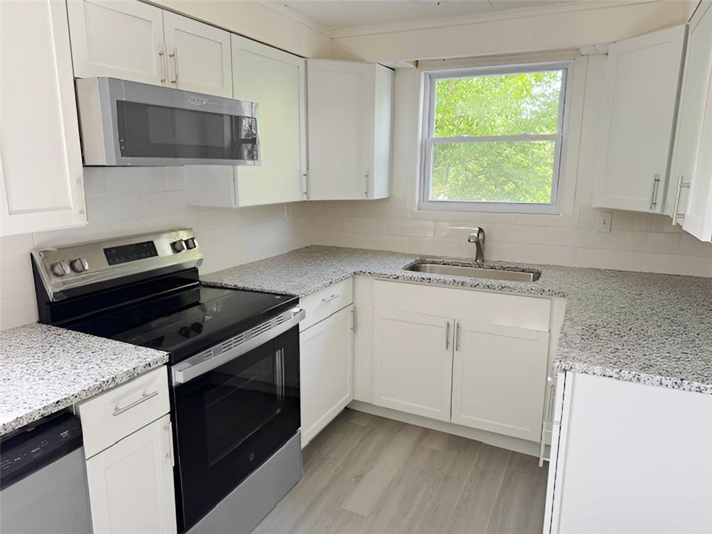 279 Olympic Road Pittsburgh, PA 15236 - Photo 11 of 25 a kitchen with granite countertop a stove a sink and a microwave