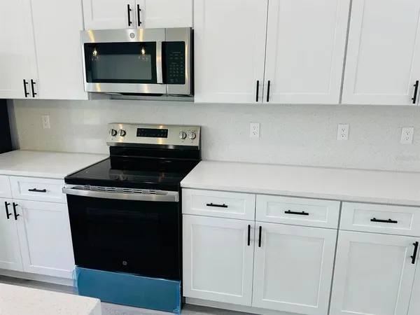 a kitchen with stainless steel appliances granite countertop white cabinets and a stove a oven with white countertops