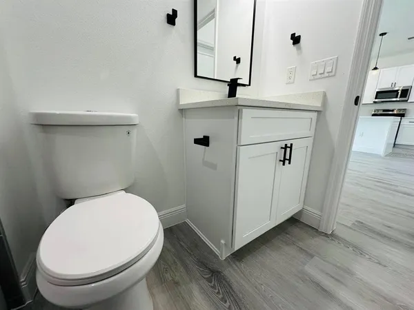a bathroom with a toilet a sink and wooden floor